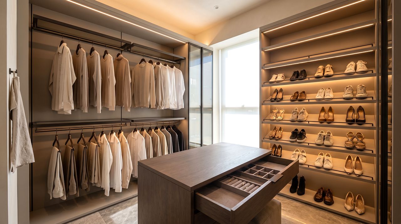 Walk-in wardrobe with hanging runs and a lit shoe wall
